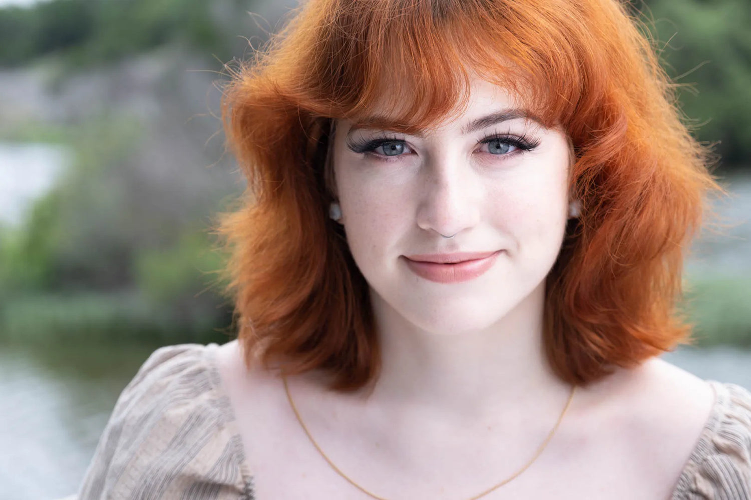 Woman with red hair and a blurred natural background. Branding