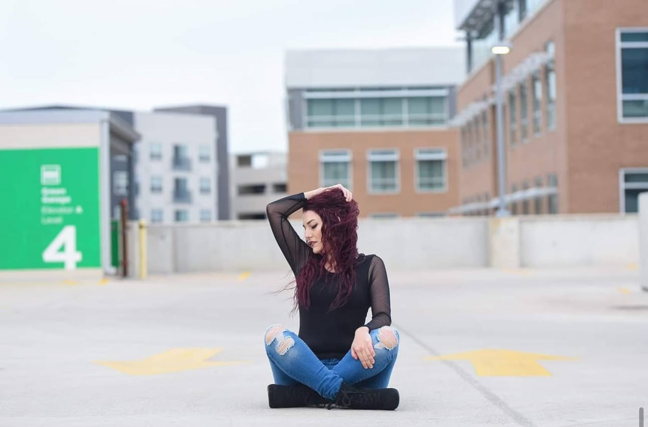 Person sitting on a parking lot with buildings in the background